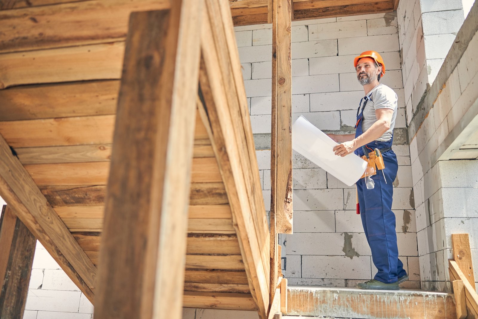 Contented builder in a helmet looking up